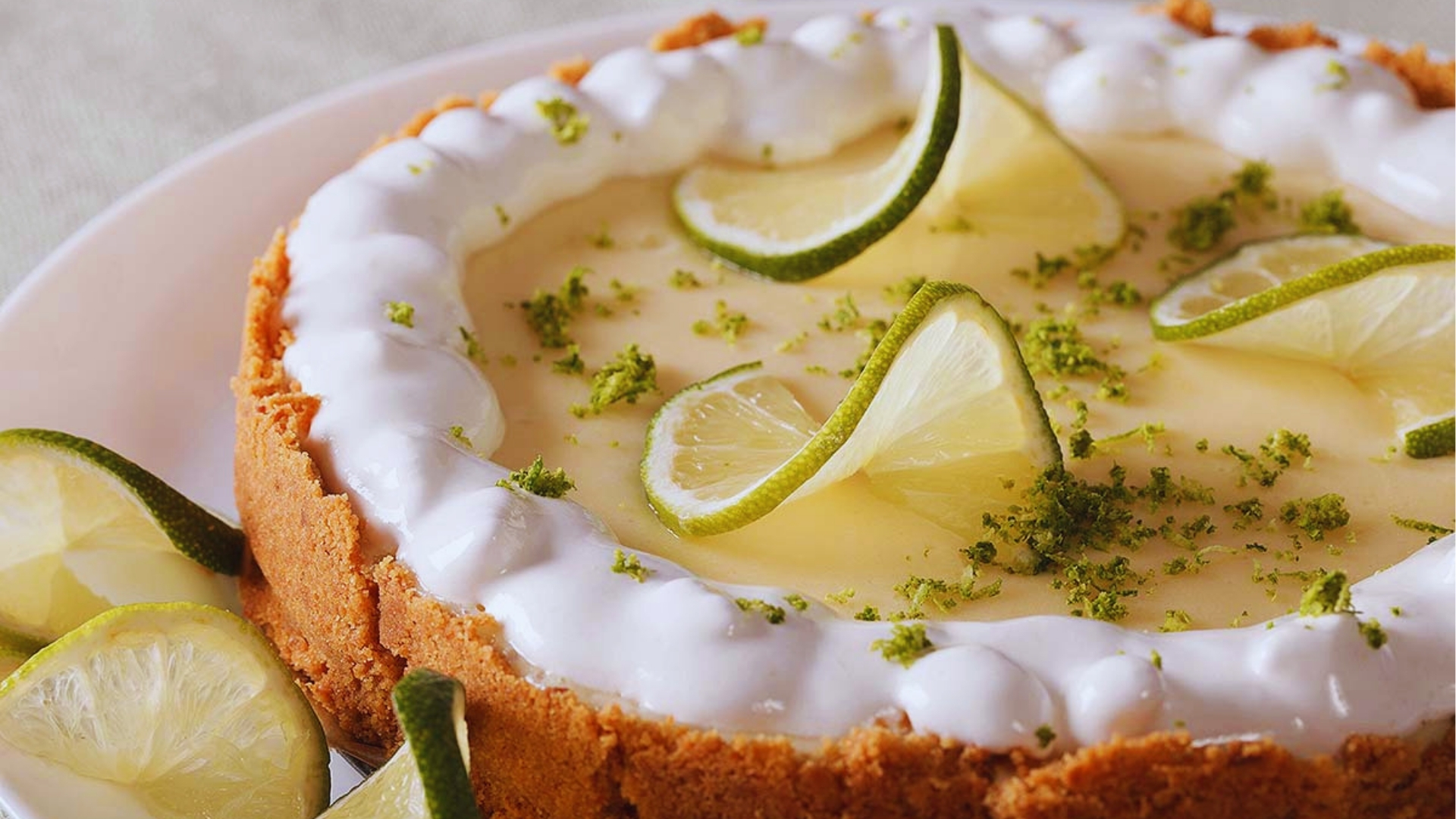 Classic Key West Key lime pie with graham cracker crust, whipped cream border, fresh lime slices, and zest topping.