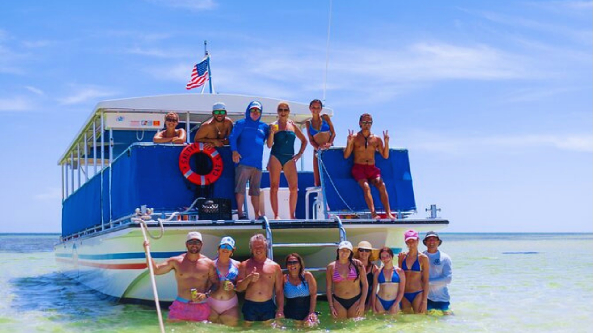 Group of tourists posing on sandbar and boat deck during Key West sandbar cruise on sunny day