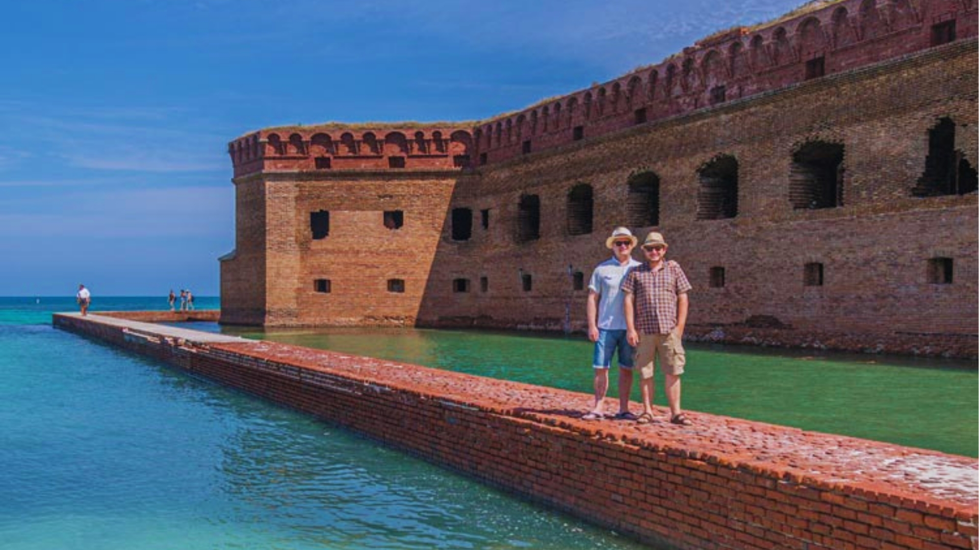 Two tourists pose on brick seawall at Fort Jefferson in Dry Tortugas National Park near Key West Florida.
