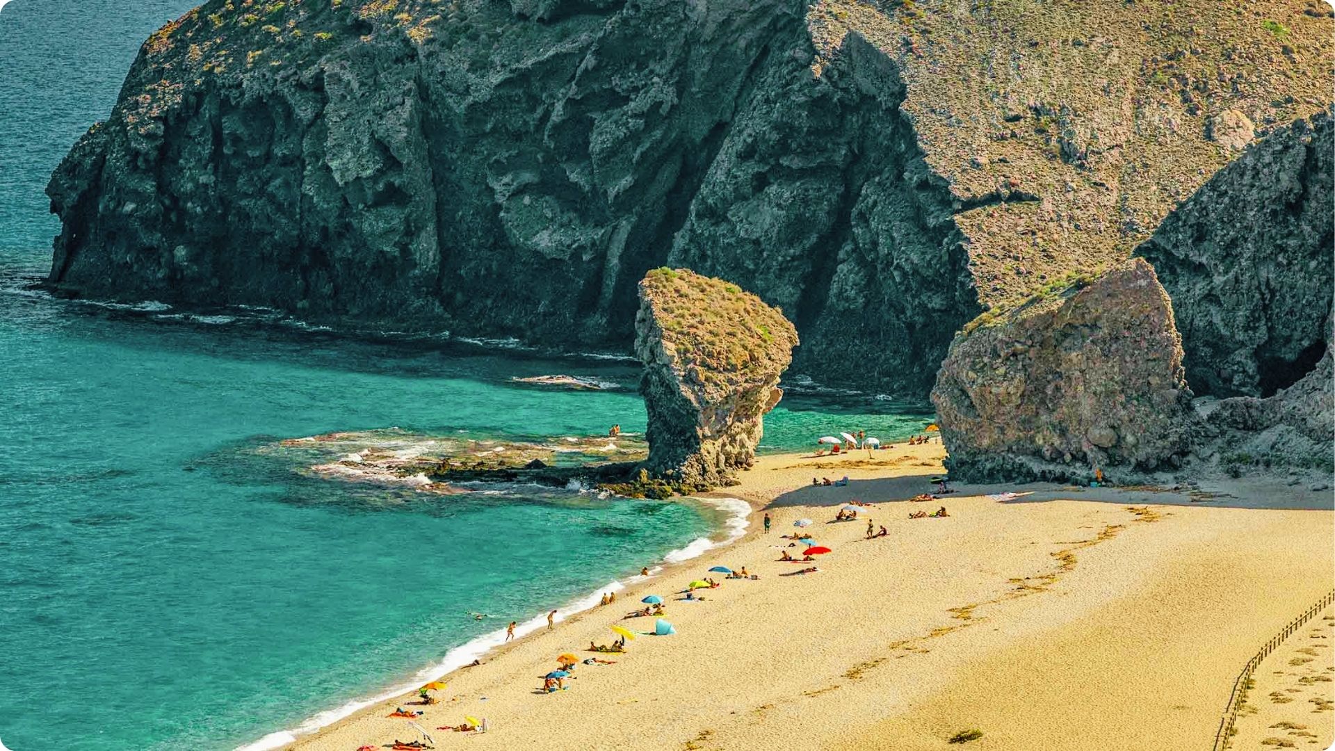 Sunbathe on golden sand at Playa de los Muertos, framed by dramatic rock formations and cliffs.