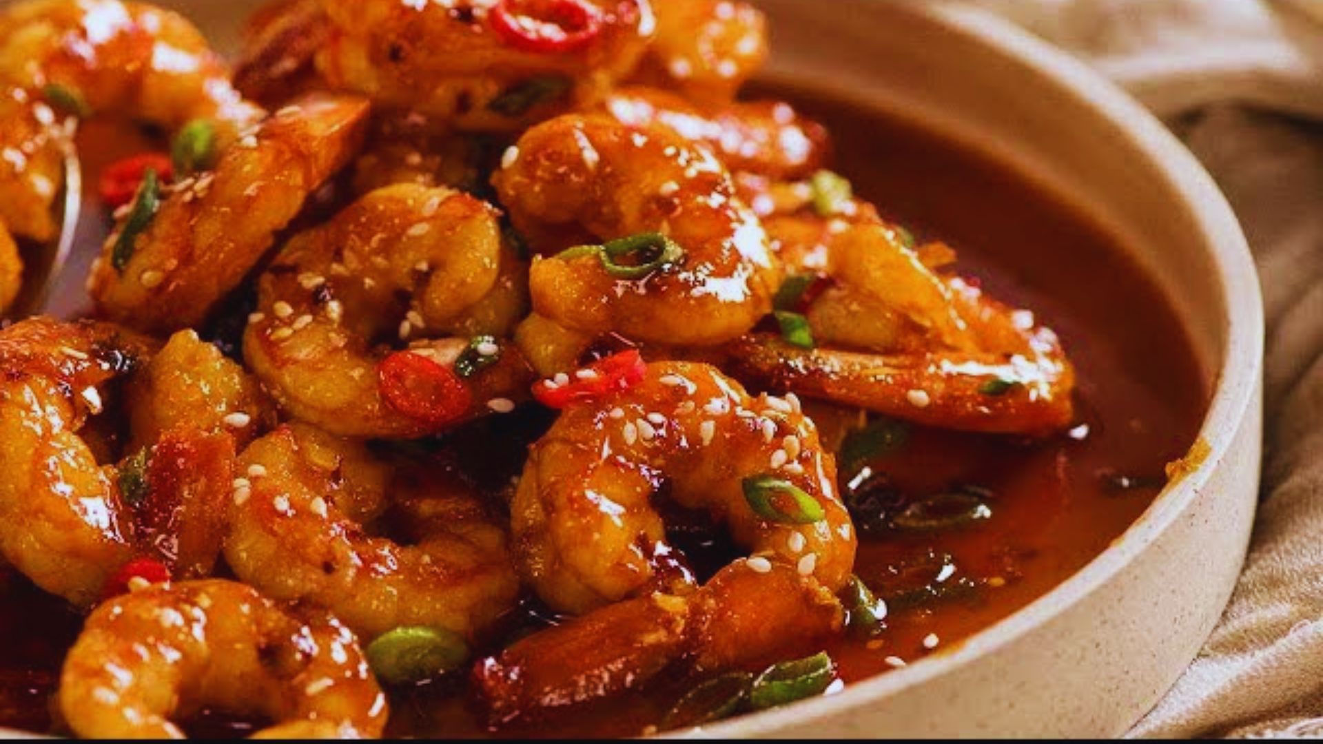 A bowl of shrimp served with a flavorful sauce and garnished for presentation.