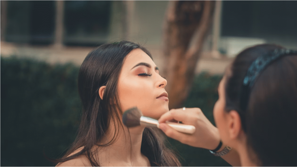 Top Makeup Academy Brampton – Enroll Today A woman applies makeup to another woman, who is seated and looking in a mirror, in a well-lit beauty studio.